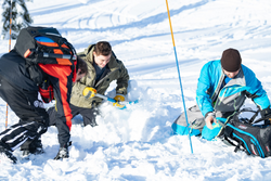 men digging in snow for AST course training